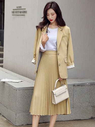 Woman wearing a long pleated skirt with a blazer.