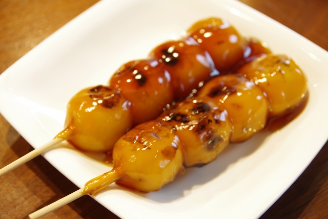 Close of a Mitarashi Dango a Japanese round shaped rice cake in a stick with a soy sauce based sauce
