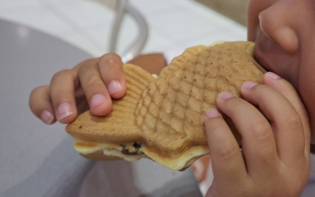 Child holding a Taiyaki, a Japanese sweet shaped as a fish