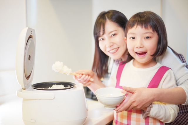 A woman and a child posing in front of a Japanese style rice cooker