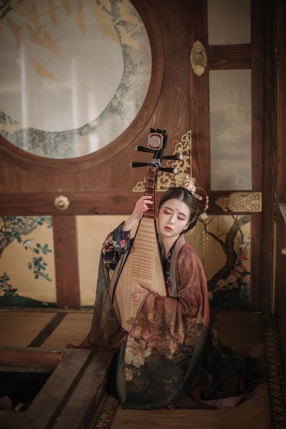 A person dressed with a Japanese style clothes holding a Biwa, an Japanese musical instrument