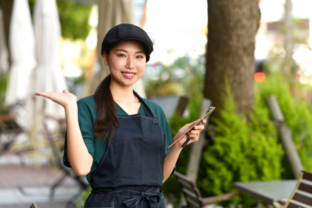 A person wearing a black apron and holding a restaurant tab on one of their hands