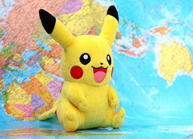 A Pikachu plushie sitting on a world map