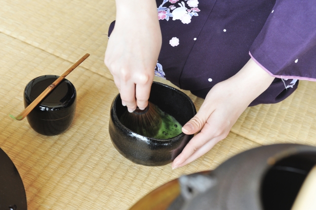 Woman whisking matcha in a chawan using a bamboo whisk