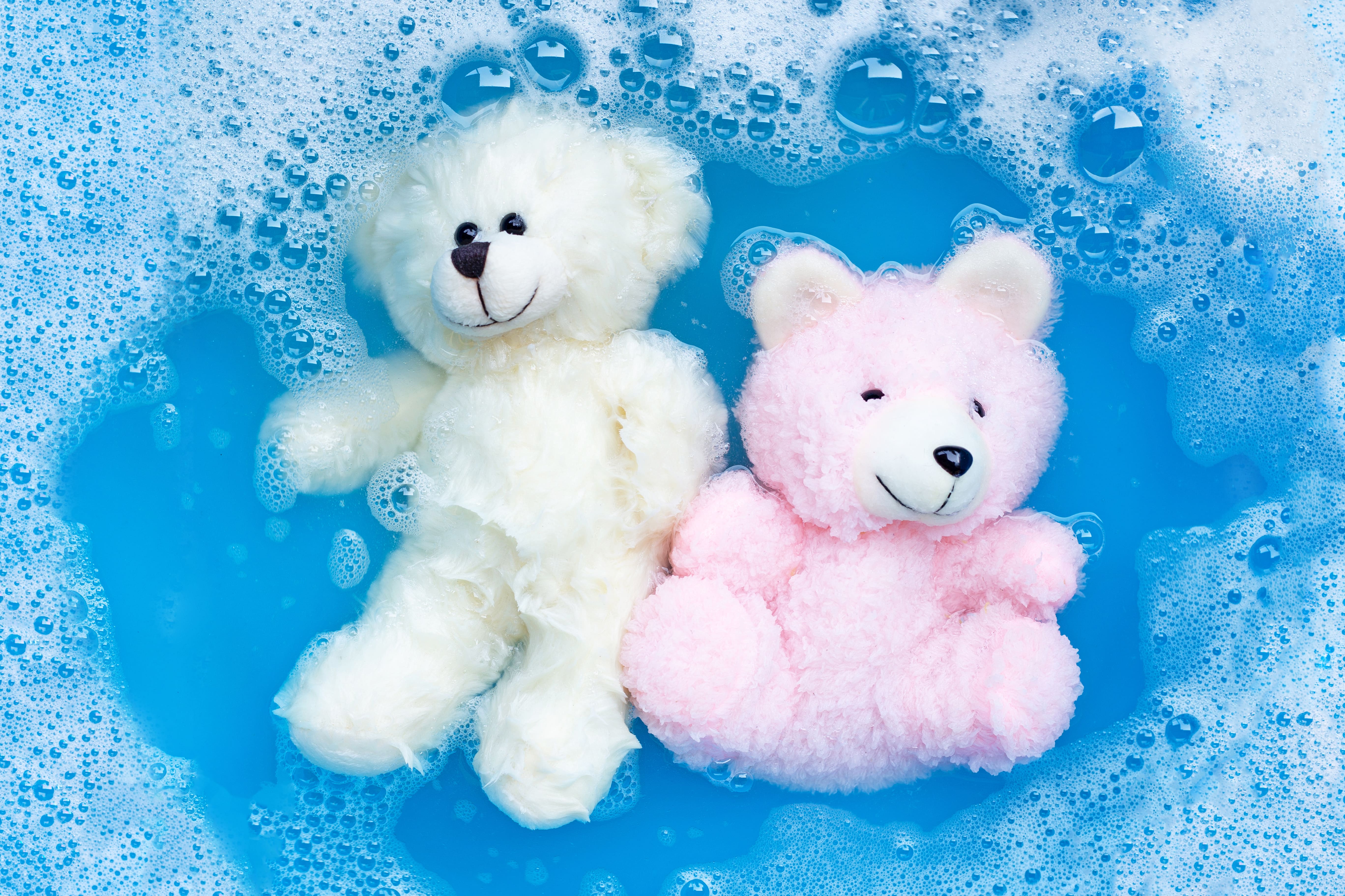 Pink stuffed bear and white stuffed bear in soapy water