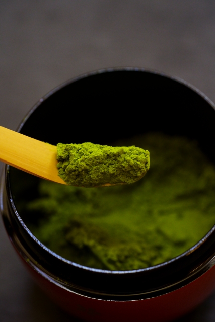 matcha powder being scooped with a bamboo tea scoop