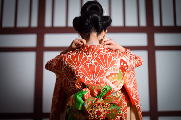 A woman in kimono from behind adjusting the neck collar of her dress