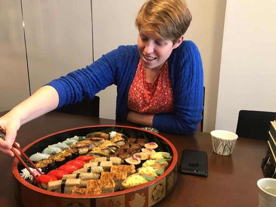 A female person getting vegan sushi out of a big plate in a restaurant in Japan