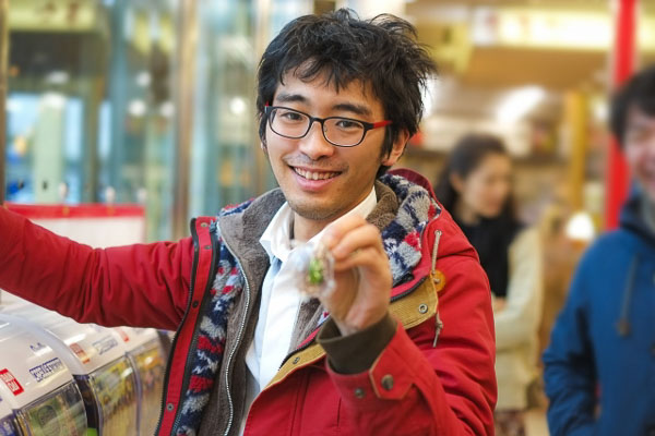 A man holding a Gacha Gacha just received from a vending machine