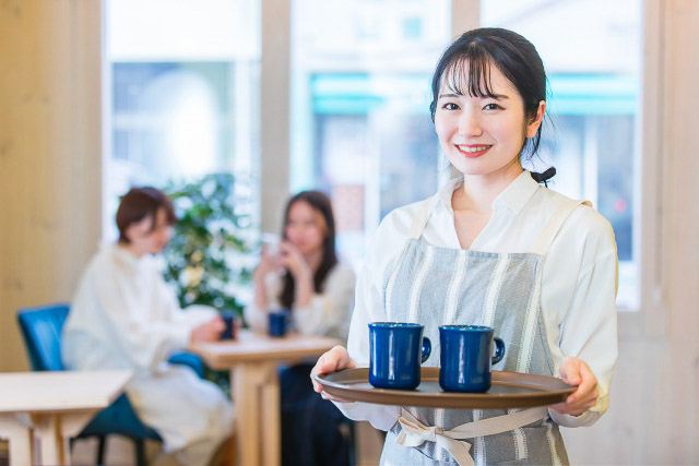  A woman holding a tray with two coffee cups in a cafe