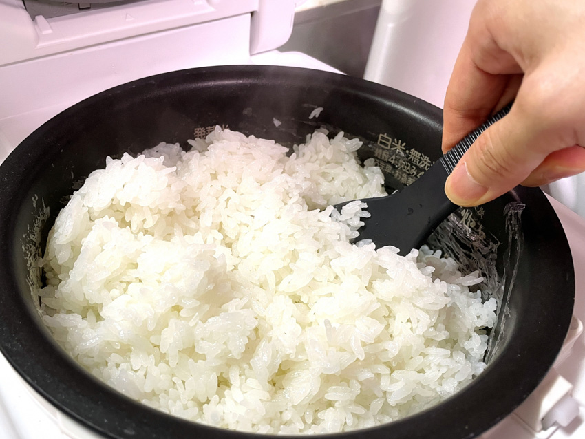 Person fluffing a pot of newly cooked rice