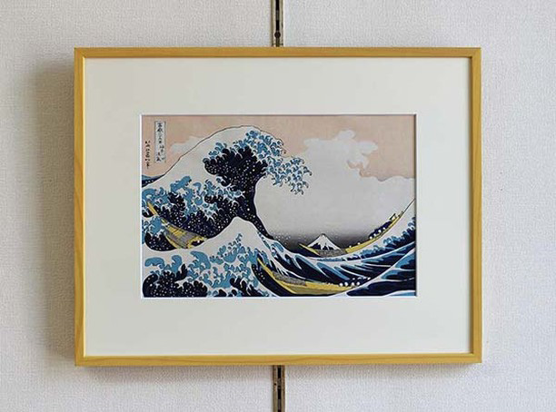 A framed woodblock print of The Great Wave Off Kanagawa hanging on a wall