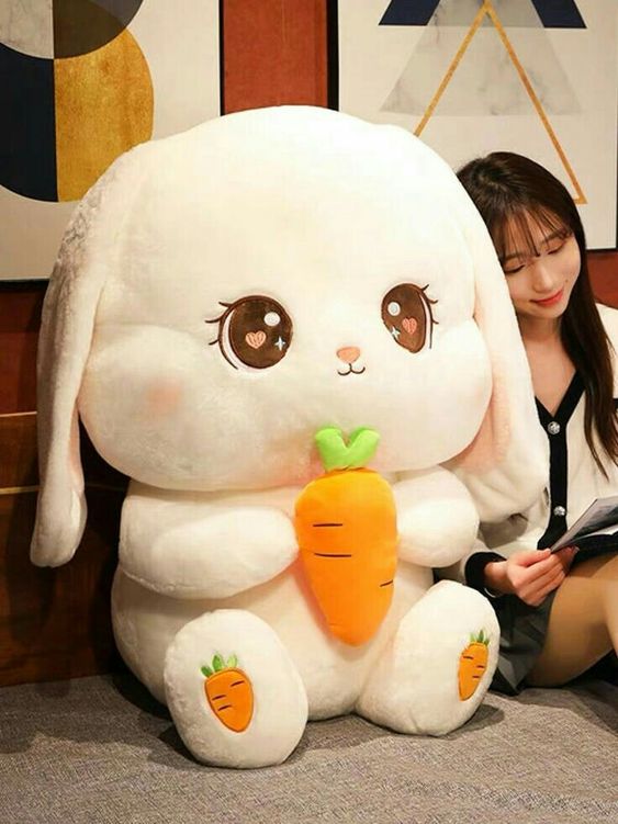 A person reading a magazine right next to a large bunny plushie