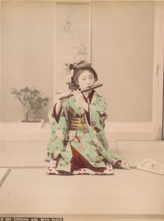 An image of a person dressed in Japanese kimono playing the flute 