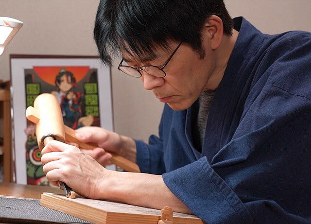 A man carving a wood block for printing.