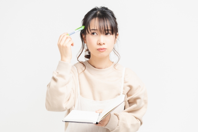 Young lady hold a pen next to her head with a thinking expression