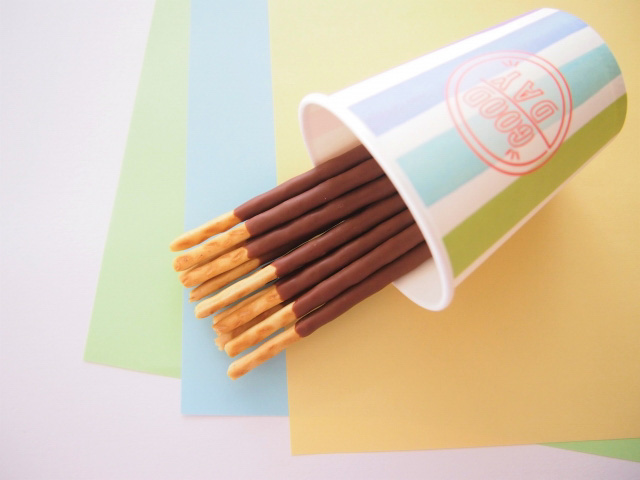 A dozen or so Pocky choco sticks in a cup sideways on a table