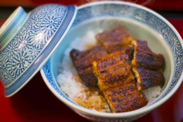 Close up of a bowl of unadon with the lid resting on the edge of the bowl