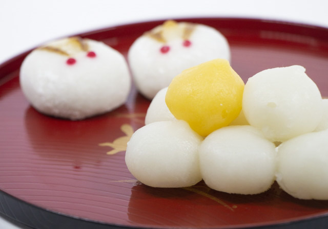 White daifuku and one yellow daifuku on a tray with Japanese New Year style decorations