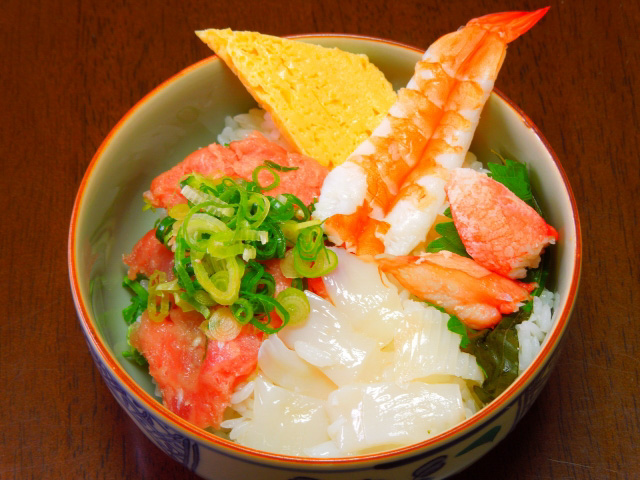 Close up of a bowl of Kaisendon with shrimp and squid on top of white rice