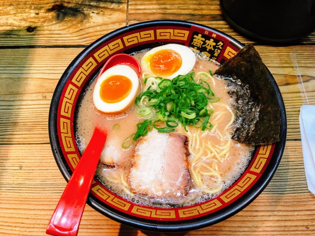 Close up image of a bowl of ramen, with eggs, meat and green onion at the top