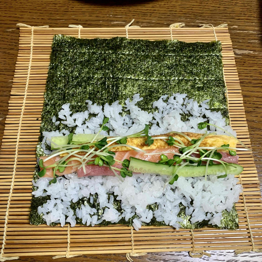 A sushi roll with ingredients before being rolled