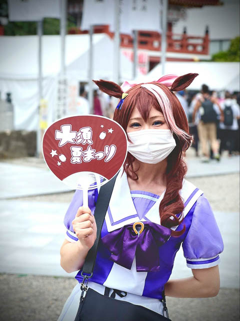 A girl in a kawaii cosplay outfit outside an event area.