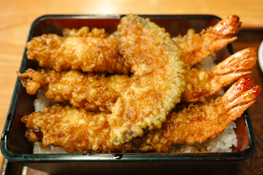 Ebi (shrimp) tempura on a bed of rice and with a slice of pumpkin tempura on top.