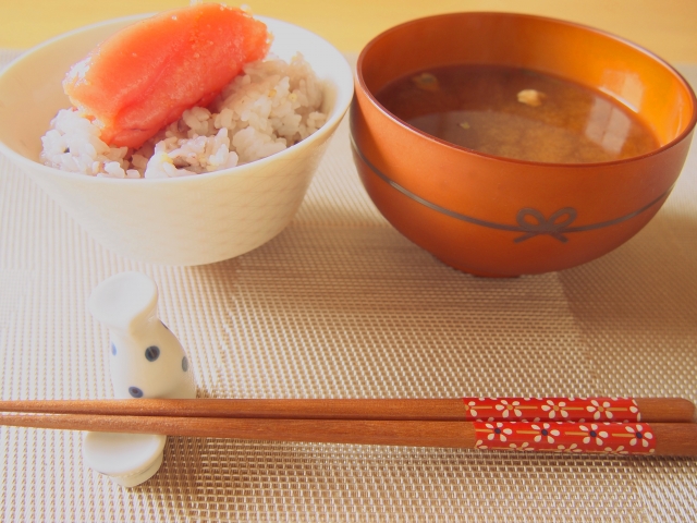 A bowl of rice with mentaiko on top and a bowl of miso soup on the side.