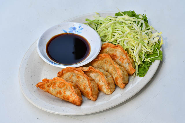 A plate of gyoza with a small plate with dipping sauce