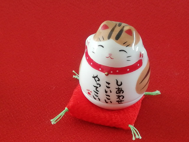 A ceramic cat figure with the words Bring me luck on it in Japanese