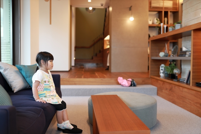 A girl sitting on the sofa wearing colorful clothes and black slippers