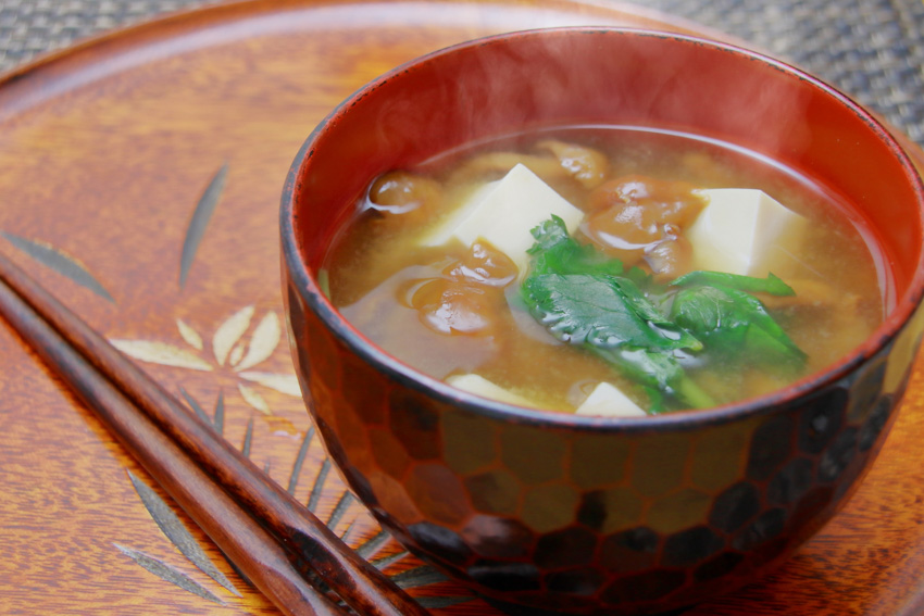 Miso soup in a bowl on a wooden tray with chopsticks on the side