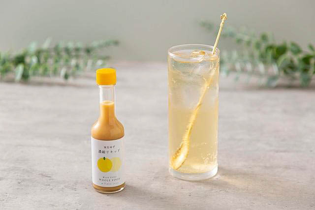 Small bottle of Yuzu concentrated liquid with a glass full of a light yellow drink