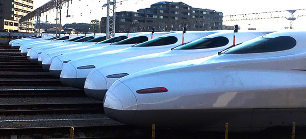 A row of twelve white Shinkansen trains lined up in a railway yard 