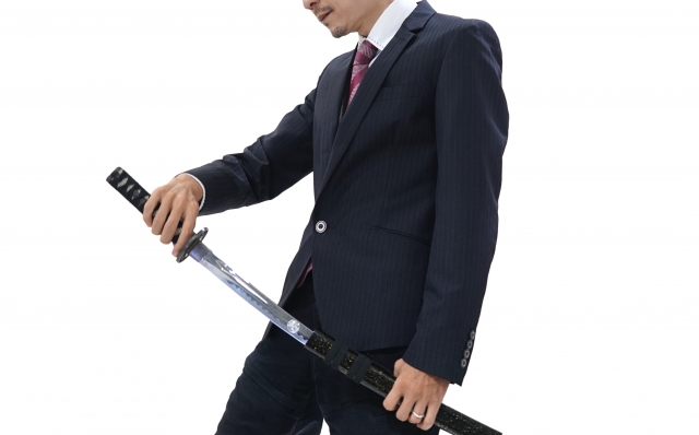 A person wearing a suit and holding a katana with one of their hands