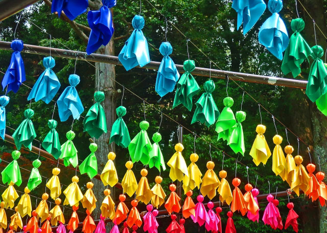 Many Teru Teru Bozu in the different colors of the rainbow hanging in rows