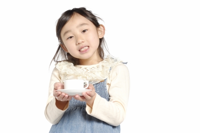 A child holding a cup of tea with both hands