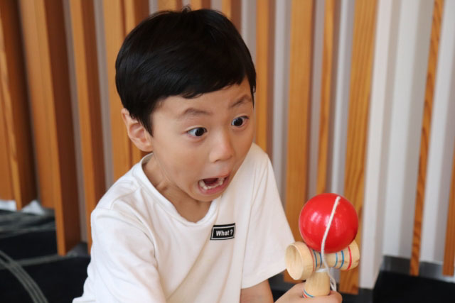 Young boy playing with a kendama and looking very exicted.