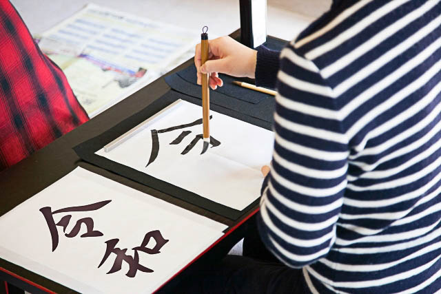 A person doing calligraphy on a low table.