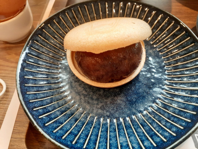 Close up of a shell like monaka on a blue plate that is opened and revealing its anko filling.