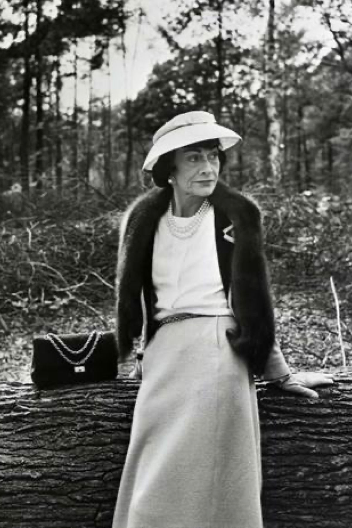 Gabrielle Coco Chanel sitting next to a Chanel 2.55 bag