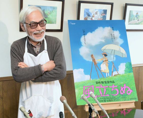 Hayao Miyazaki standing next to the poster of The Wind Rises