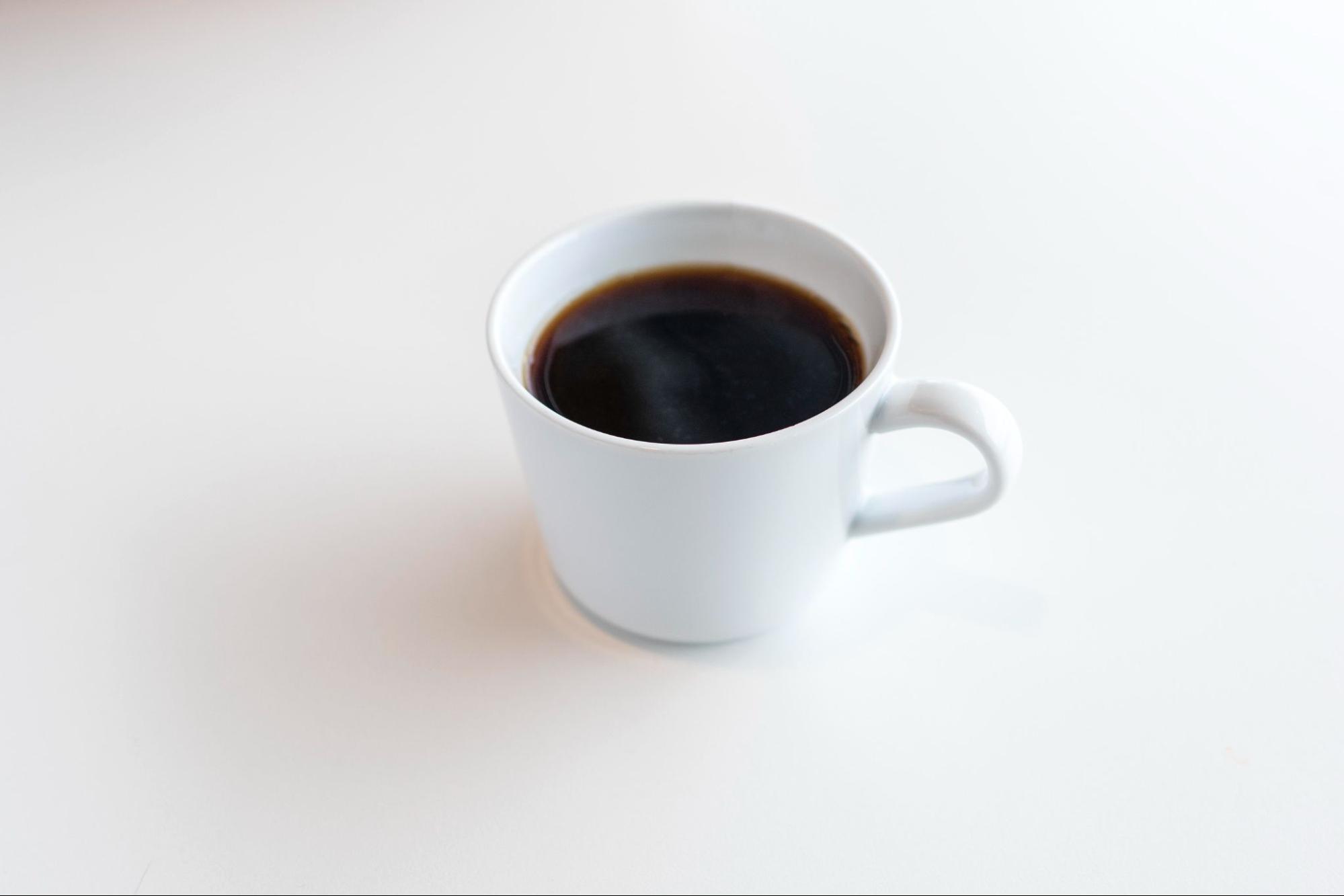 Cup full of coffee on a white surface