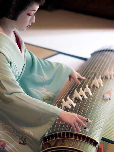 An image of a person dresses as a Maiko playing the Japanese instrument Koto