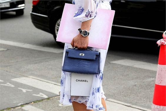 Woman walking with a Hermes handbag and a Chanel shopping bag