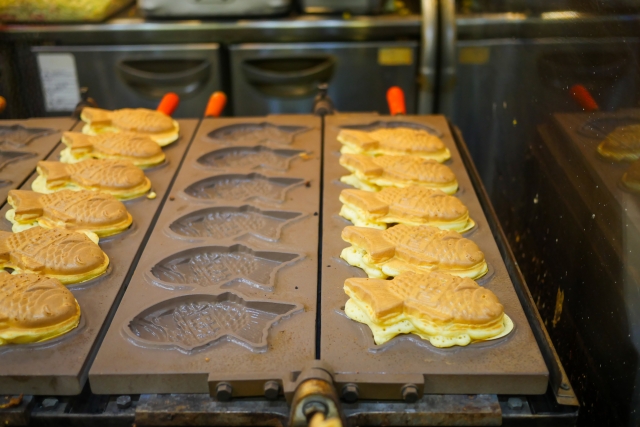 A fish shaped hot plate with cooked Taiyaki on top of it