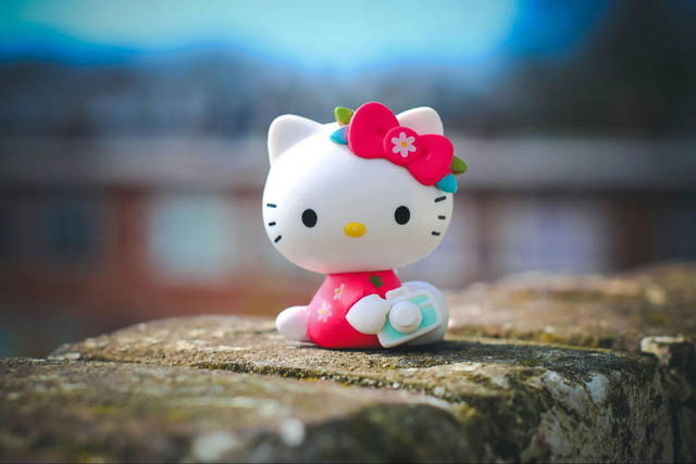 A Hello Kitty doll sitting on a rock wall.