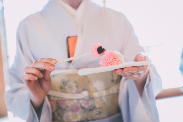 A person wearing a traditional kimono holding a plate with a Japanese dessert on it