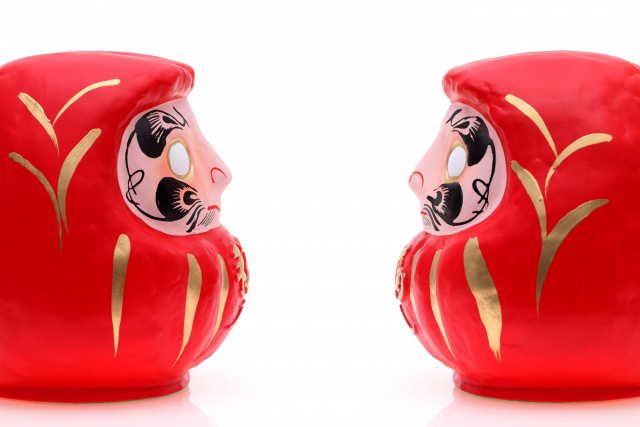 Two daruma dolls in profile facing each other